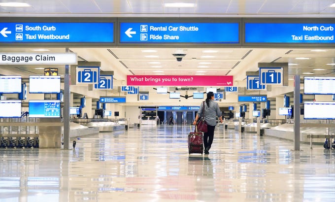 A lone traveler enters an empty baggage claim area in Terminal 4 at Sky Harbor International Airport in Phoenix. Airlines are reducing flights due to the coronavirus COVID-19 outbreak.