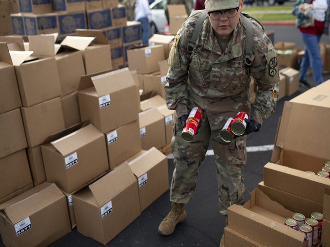 Volunteers with United Food Bank and members of the Arizona Army National Guard pass out food to those in need at the Mesa Convention Center in Mesa on March 27, 2020.