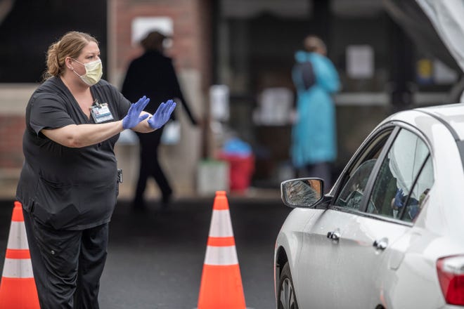 An Abington Hospital worker asks a person driving to up to be tested for the coronavirus to stop their car and wait to make sure they has an appointment to take the test on March 17, 2020.  Abington Jefferson is operating a drive-up site for coronavirus testing, for patients referred by doctors in the Abington Jefferson network.  It is in the parking lot of an outpatient office across from Old York Road from the main hospital. Dr. Gerard Cleary, the hospital's Chief Medical Officer, says the site was picked, "So we can completely separate these patients from all the other patients on campus," says
