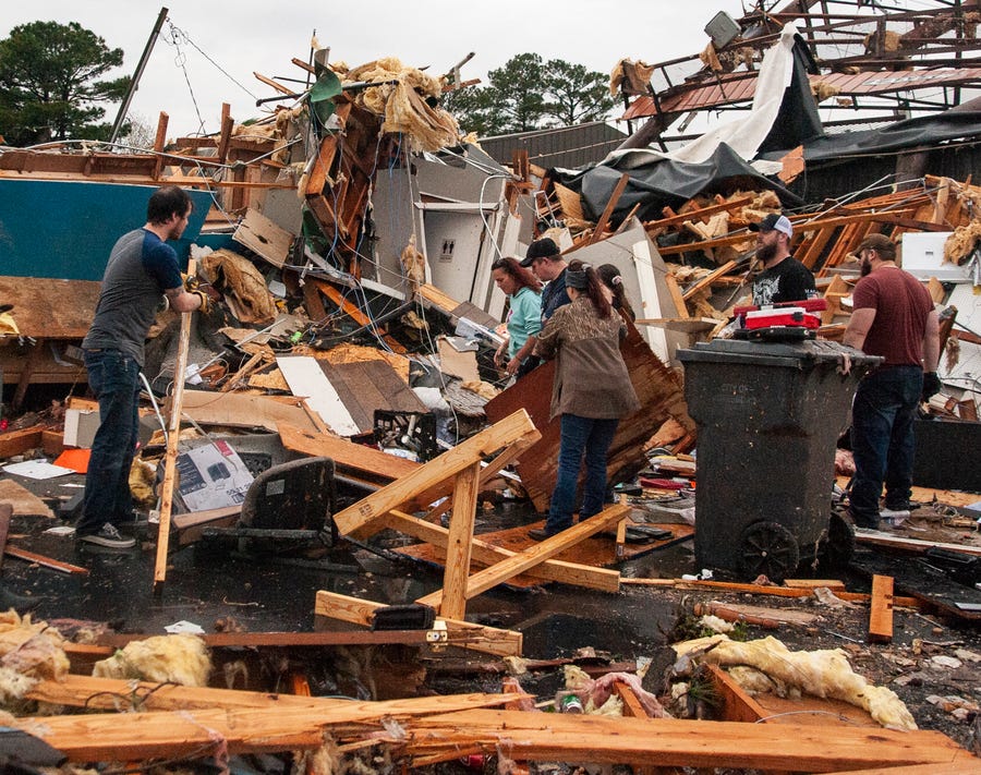 A group of people help clear debris and salvage items from Pawn Depot after a tornado touched down Saturday, March 28, 2020, in Jonesboro, Arknasas. 