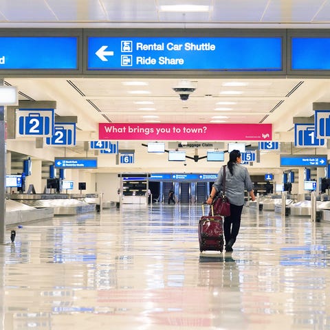 A lone traveler enters an empty baggage claim area