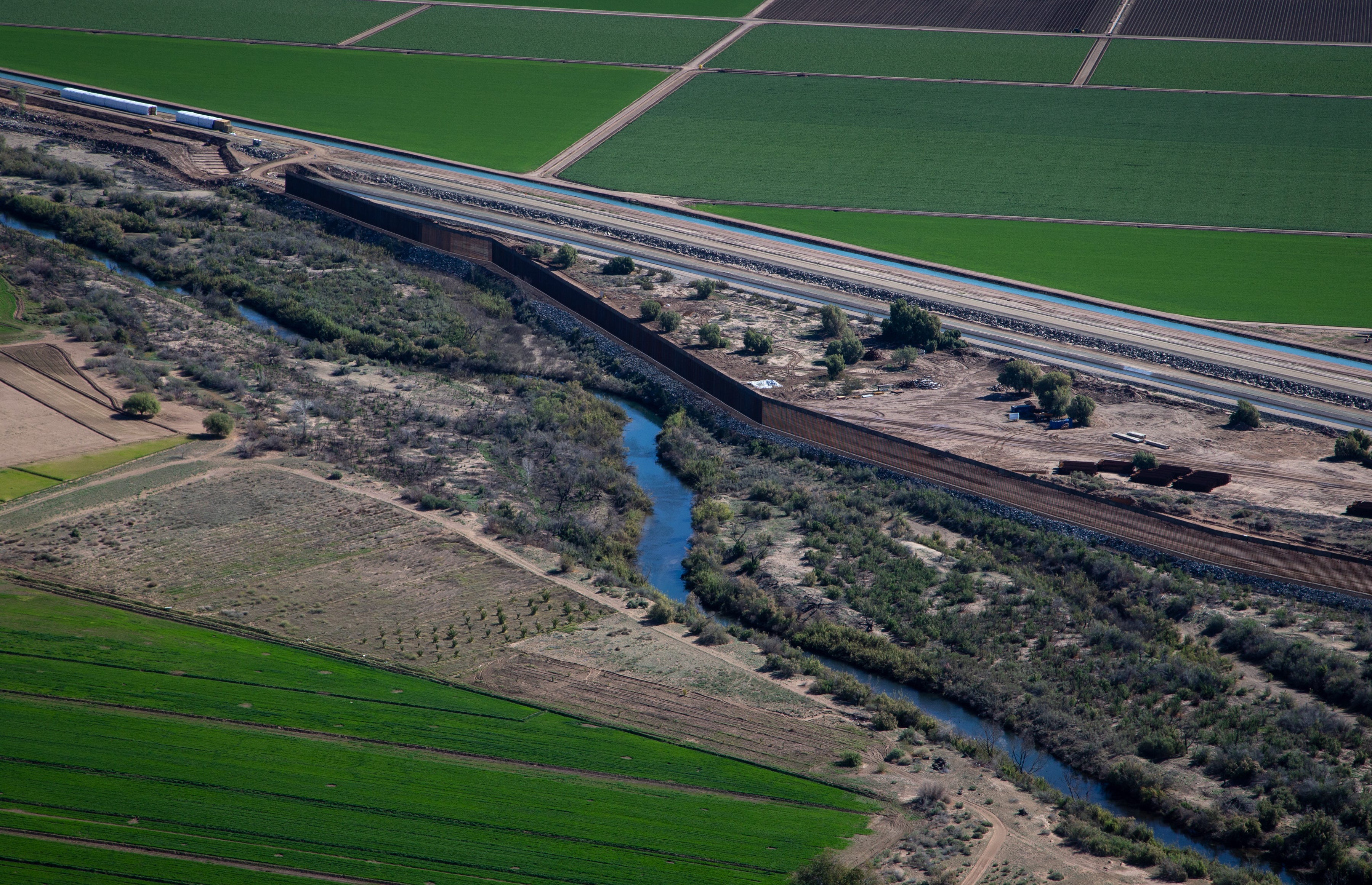 The Colorado River flows next to the border wall south of Morelos Dam in Mexico.