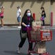 A woman pushes her grocery cart back to her vehicle while shoppers keep social distance between each other because of the new coronavirus pandemic while lining up to enter the Trader Joe's at the Town and Country Shopping Center in Phoenix on March 31, 2020.