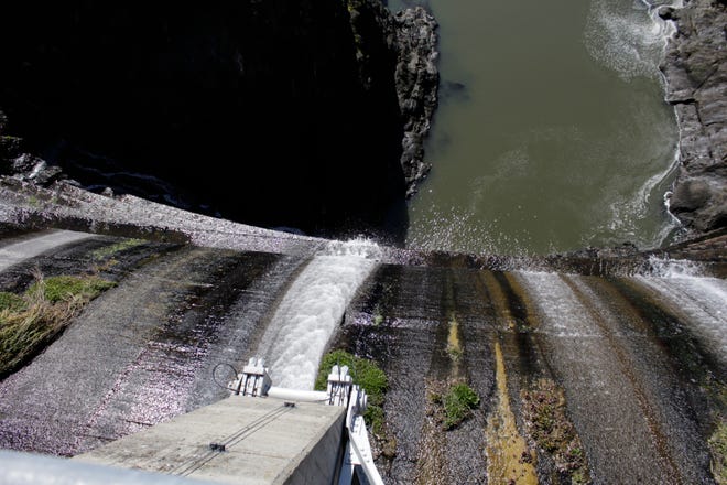In this March 3, 2020, photo, excess water spills over the top of a dam on the lower Klamath River known as Copco 1 near Hornbrook, Calif. A plan to demolish four dams on California's second-largest river to benefit threatened salmon has sharpened a decades-old dispute over who has the biggest claim to the river's life-giving waters. The project, if it goes forward, would be the largest dam demolition project in U.S. history and would include the Copco 1 facility pictured. (AP Photo/Gillian Flaccus)