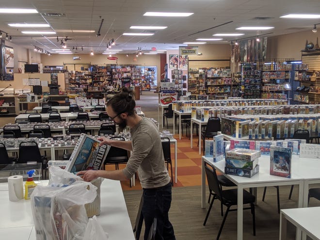 Andy Brown packs up board games at the empty Greenfield Board Game Barrister to be delivered to customers along with their food from Oak & Shield Gaming Pub. Staff are choosing games through Board Game Barrister's online personal shopper service.