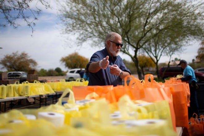 Glendale Mayor Jerry Weiers helps fill bags full of cleaning supplies to be handed out to the needy at the Vineyard Church of North Phoenix in Glendale, Ariz., on April 1, 2020.