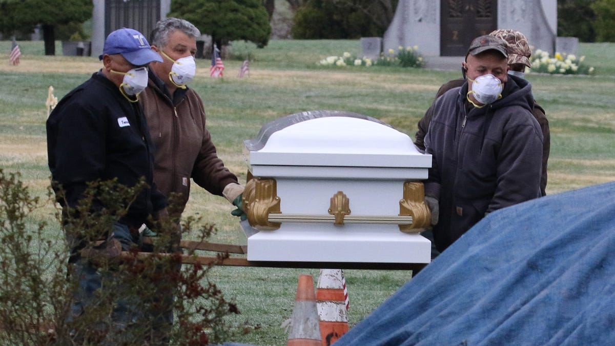 Funeral workers supervise the grave site ceremony that limits attendance to immediate family members during a funeral at East Ridgelawn Cemetery in Clifton, NJ on March 30, 2020 during the COVID-19 pandemic. 