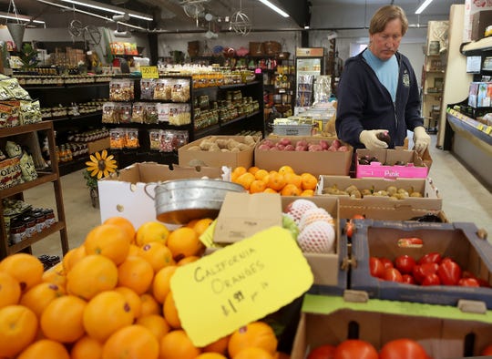 Jon Regusci, of Poulsbo, grabs a couple of avocados as he and wife Beckie purchase produce at Olmsted's Nursery in Poulsbo on Friday, April 3, 2020. 