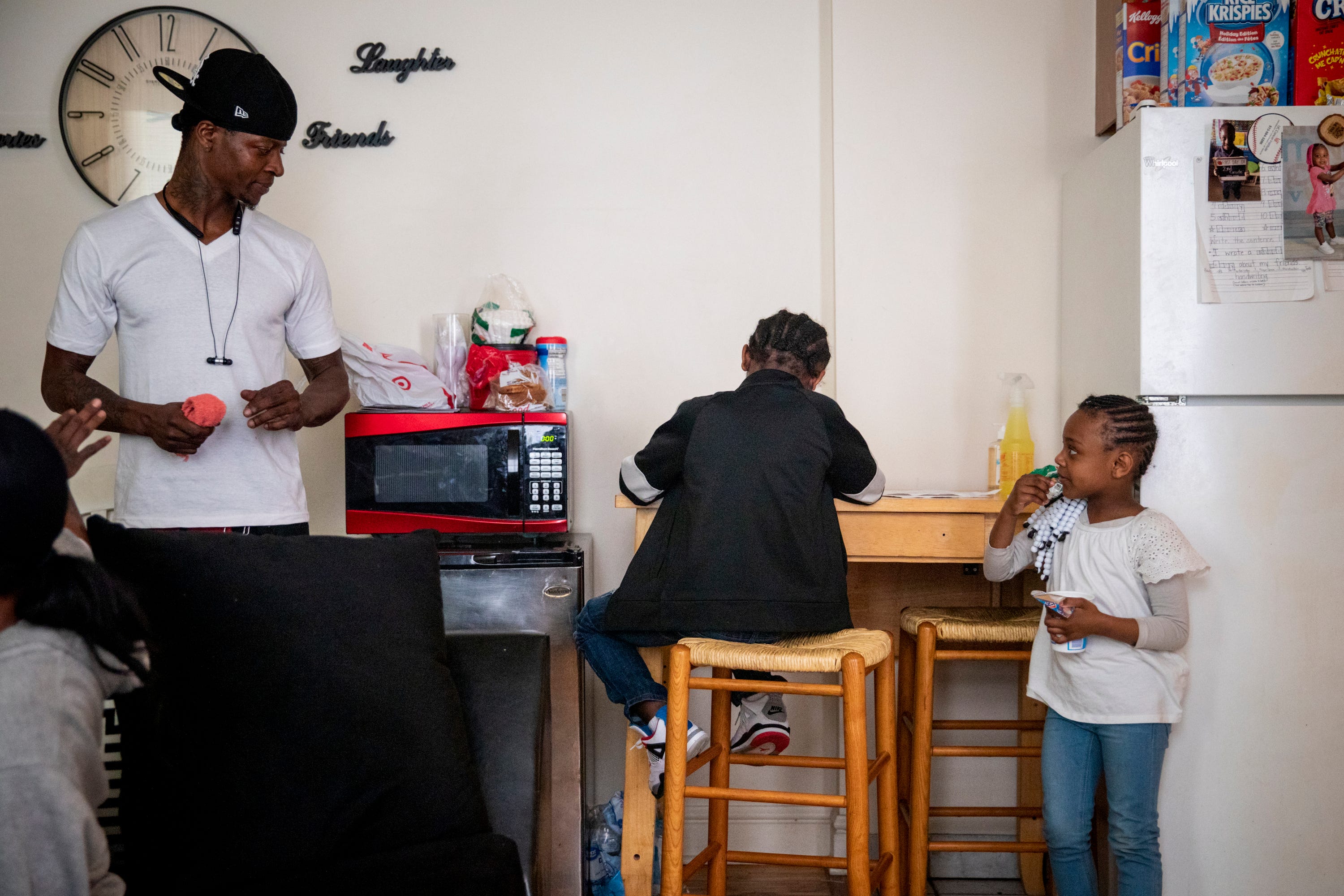 Sinaca Wagoner, Jr. 7, works on his school work while his dad and sister watch in their apartment in Lower Price Hill on Thursday, April 2, 2020. Sinaca Jr. is in the second grade at Cincinnati College Preparatory Academy. 