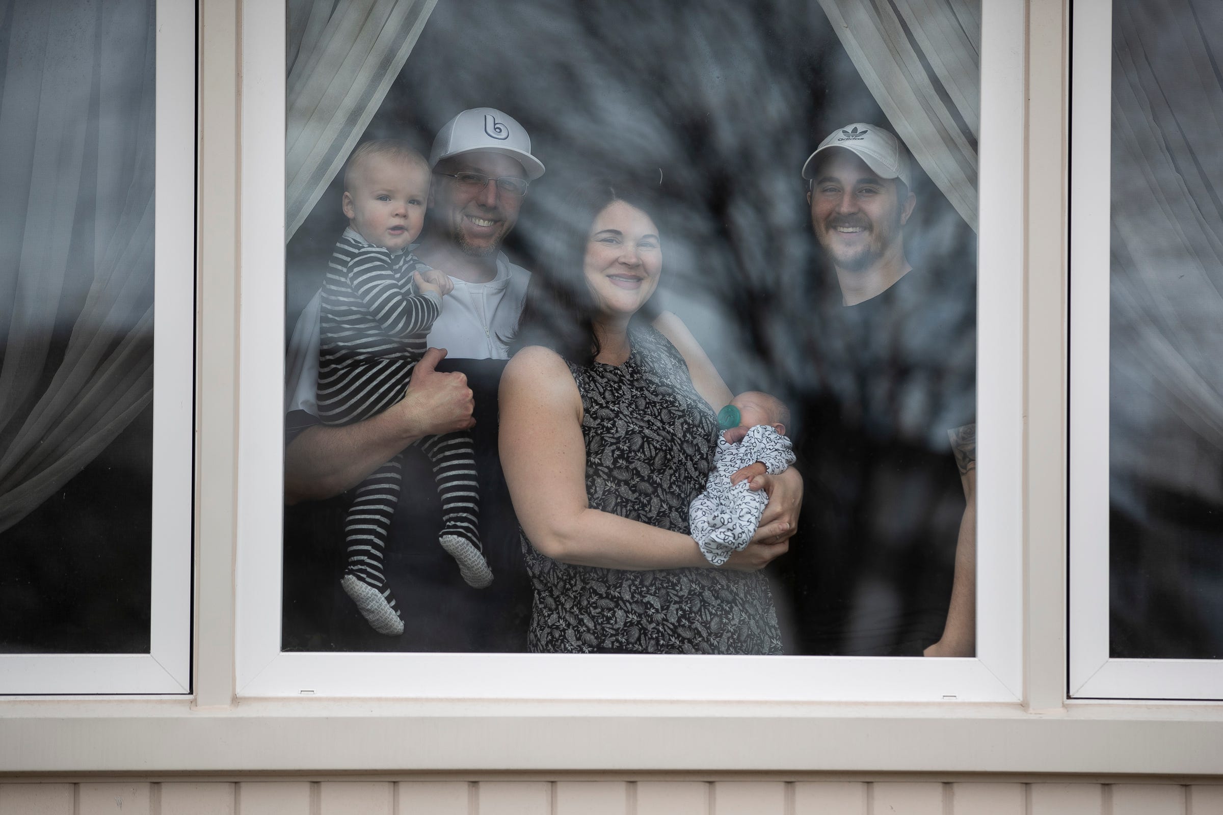 Trevor and Jennifer Thompson with their sons Mack, 1, Hollis, 3 days, and Tim Vigus, 24, pose for a photo at the their home in Warren, Tuesday, March 31, 2020.