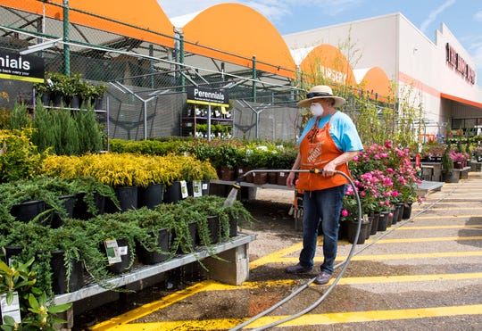 Garden associate at The Home Depot Sarah Johnson waters plants with a mask on to protect herself from the spread of COVID-19 Saturday afternoon, April 4, 2020. 