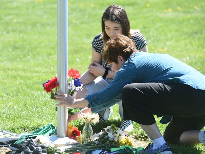 Two people stop by the flagpole at the entrance to the Wilson Complex Saturday afternoon. They placed flowers in memory of Gary Kessler, who died Friday.