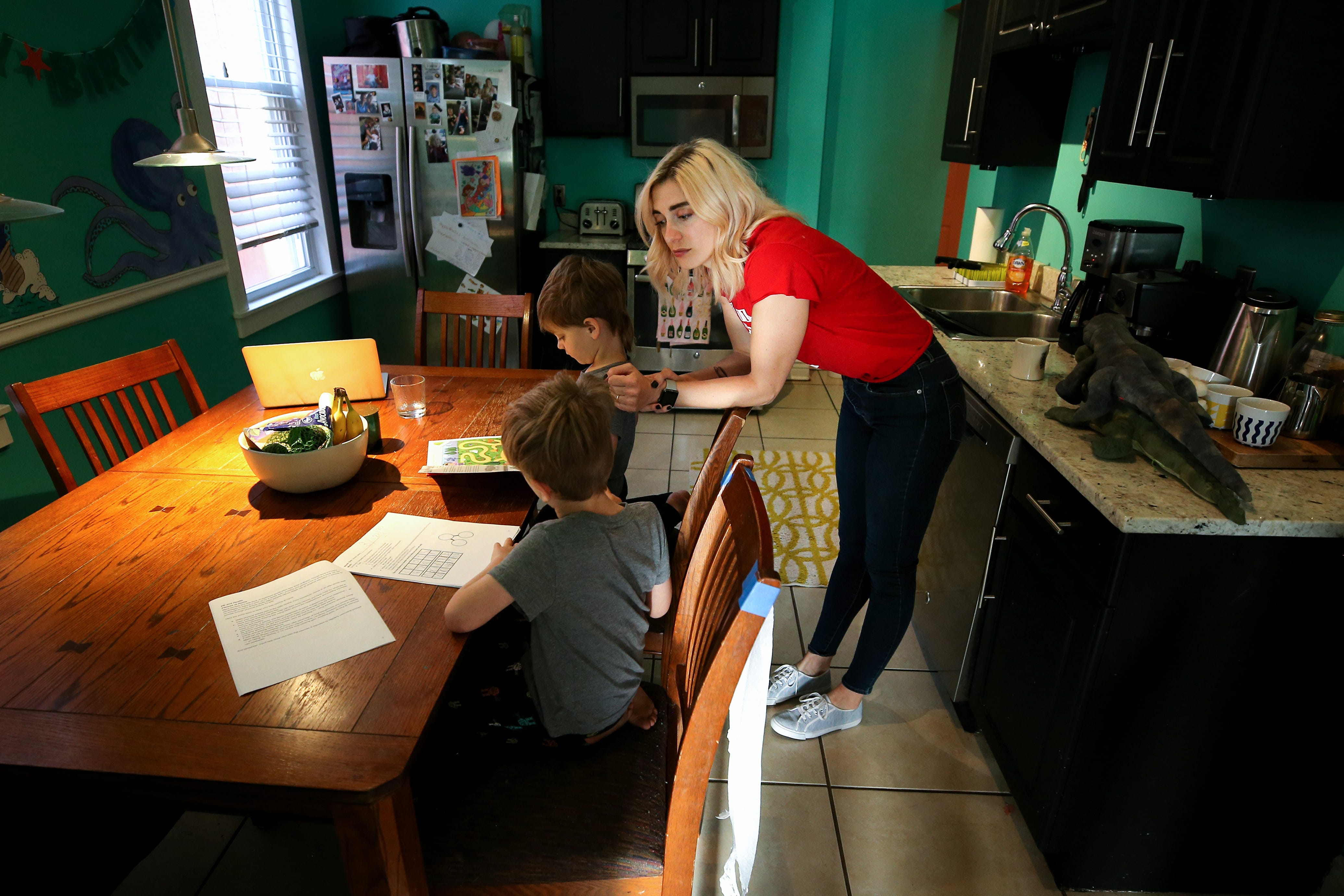 Emily Minelli, a Princeton High School French teacher, begins the day with educational work with her two sons, Nico, 3, top, and Tommy, 6, bottom, Thursday, April 2, 2020, in Cincinnati's Northside neighborhood