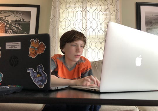 Sam Clevenger worked on his homework during the first day of NTI learning. Sam, 14, is in high school at J. Graham Brown School. His brother, Ben, was learning in his middle school class in a separate area at home. 