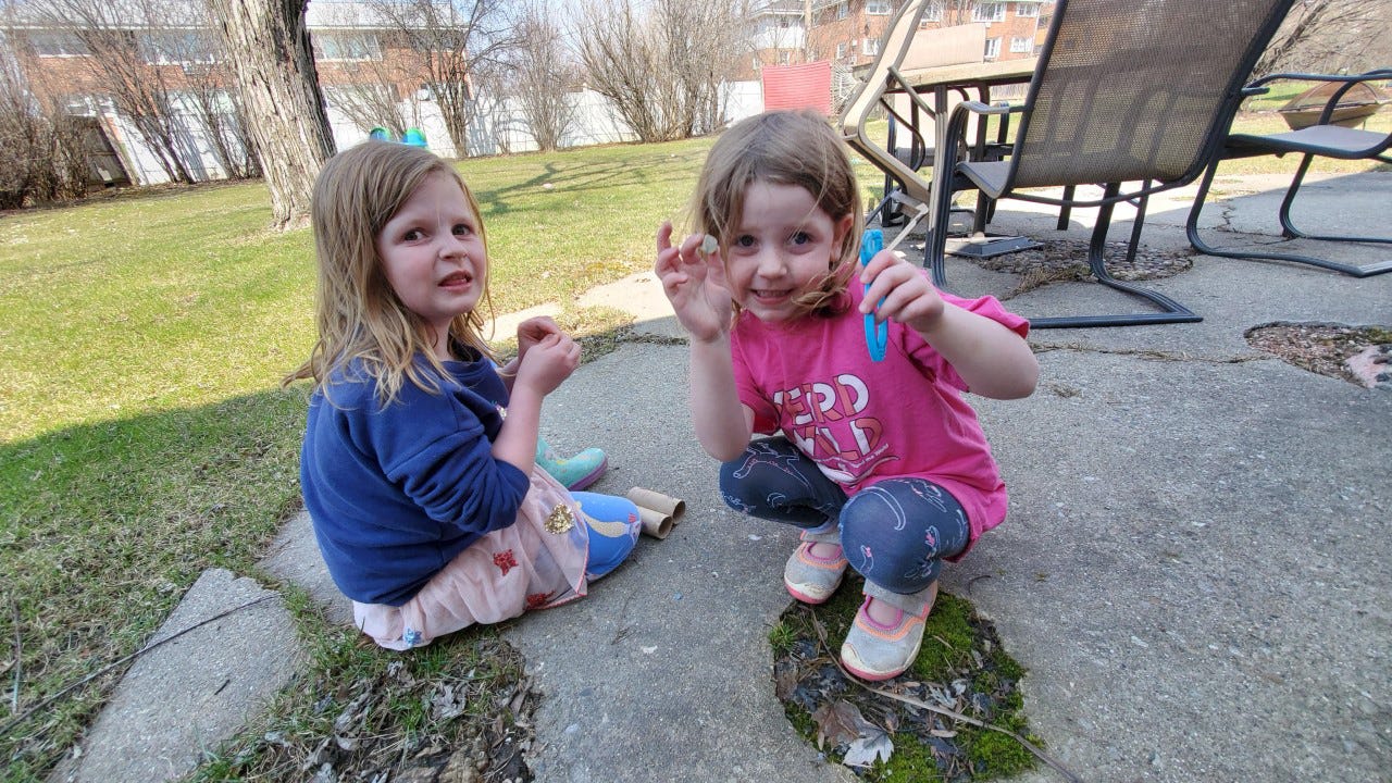 Annie and Lucy Fladten play in their yard. Their mom and dad are juggling working at home with serving as their daughters' teachers.