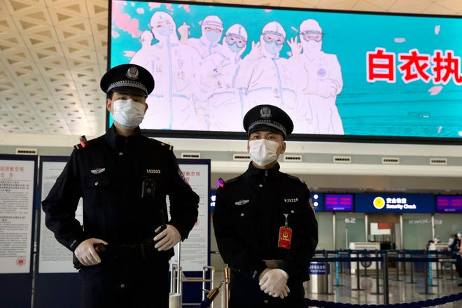 Police officers wearing face masks to protect against the spread of new coronavirus stand guard at Wuhan Tianhe International Airport in Wuhan in central China's Hubei Province, April 8, 2020.