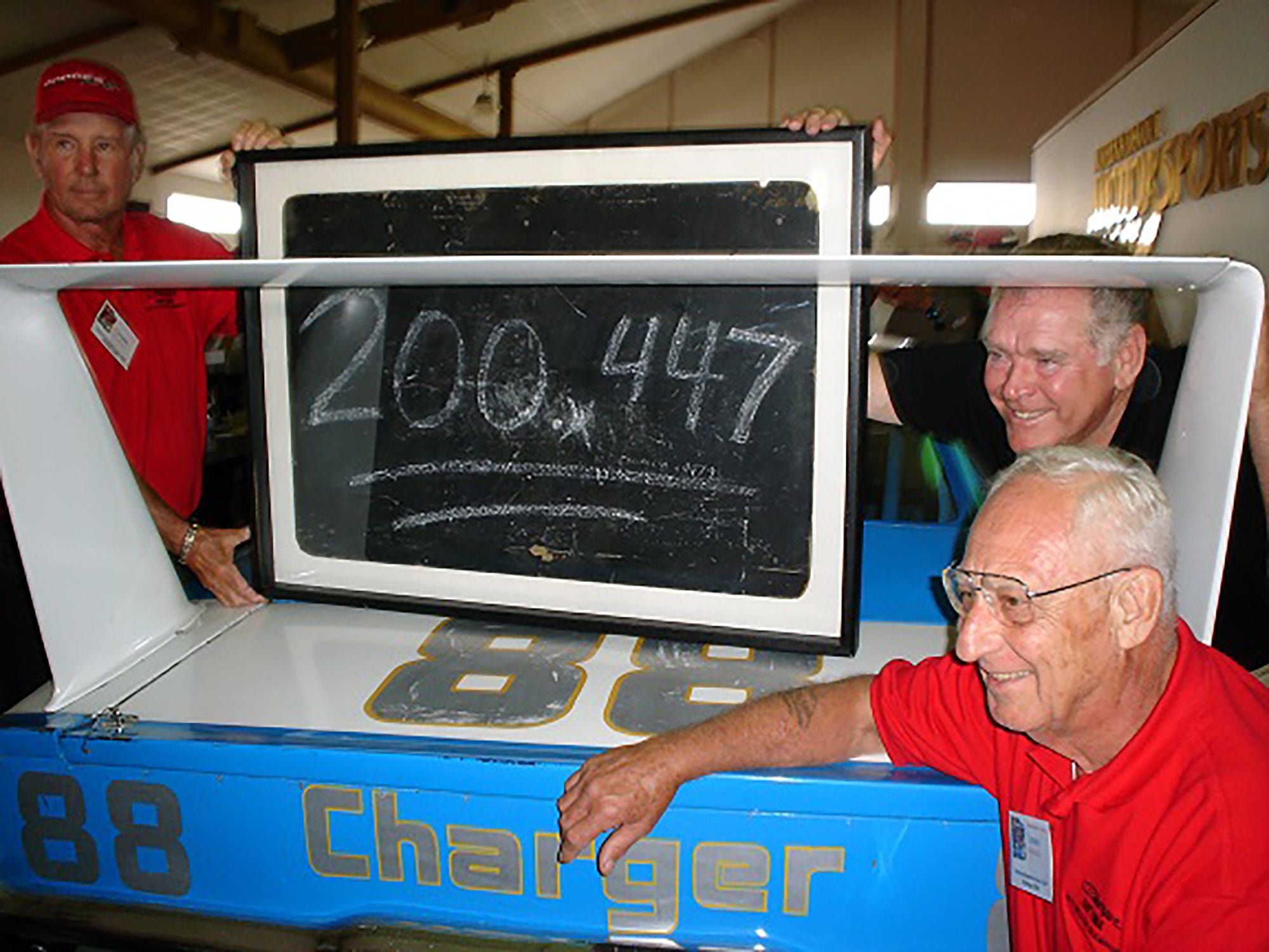 Larry Rathgeb, right with driver Buddy Baker, just behind him and Charlie Glotzbach, another NASCAR driver on the left, have their photo taken with a replica of the car that Rathgeb was the lead engineer for the car that on March 24, 1970, broke one of racing's most significant milestones, the 200 mph closed circuit track lap.