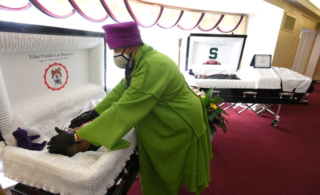 Sandy Brown touches the forehead of her late husband, Freddie Lee Brown Jr., after she cries over her late son, Freddie Lee Brown III, right. They both recently died from COVID-19 three days apart.