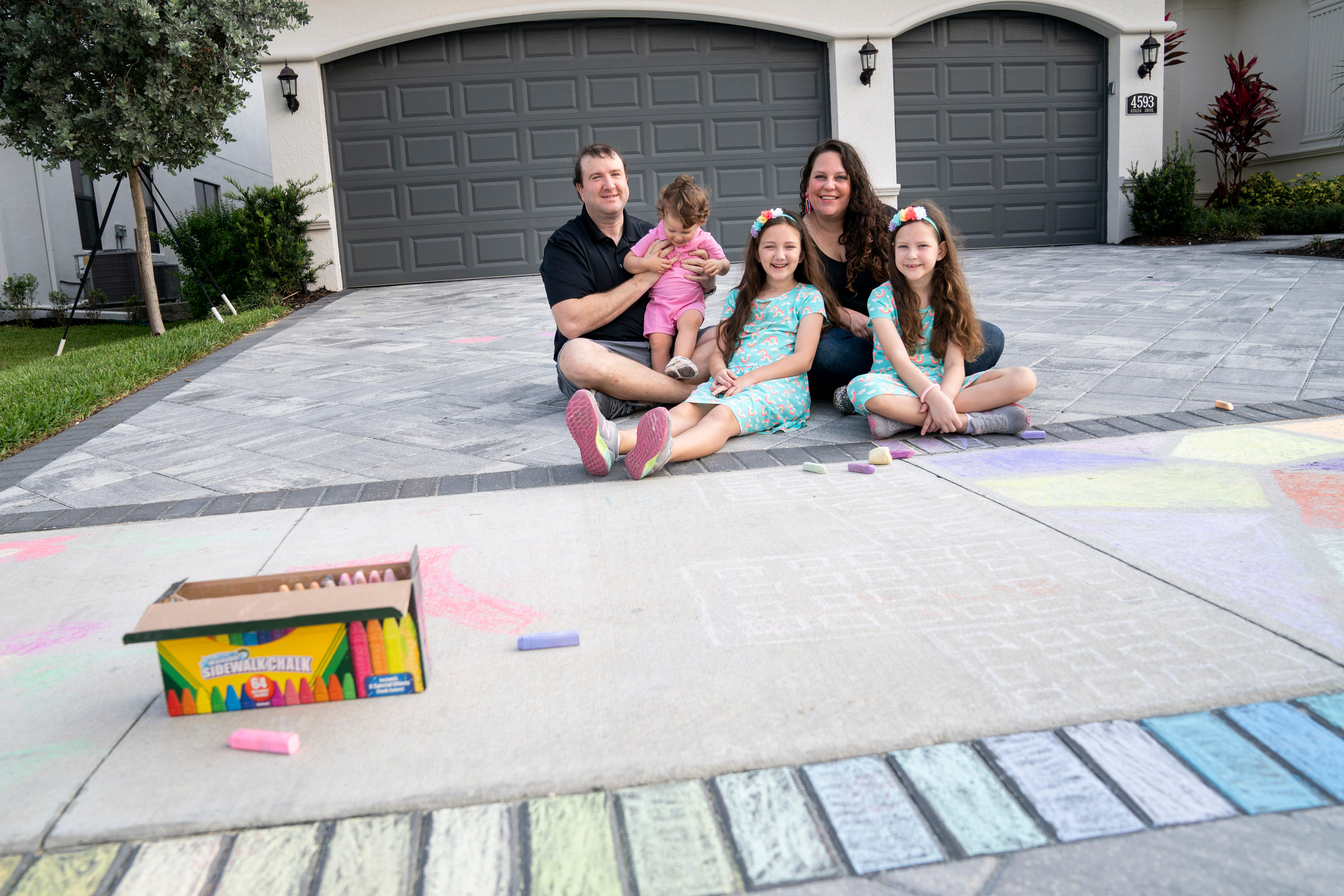 From left to right: Deric Long, Parker Long, 1, Delaney Long, 9, Ashley Long, and Brooklyn Long, 7, pose for a portrait at their home in North Naples on Friday, April 10, 2020. The Longs have been finding new activities to keep themselves busy, like coloring with chalk, doing arts and crafts and having family game nights, which has been Delaney's favorite part. "We've been spending a lot more time as a family, which is awesome," Deric Long said.