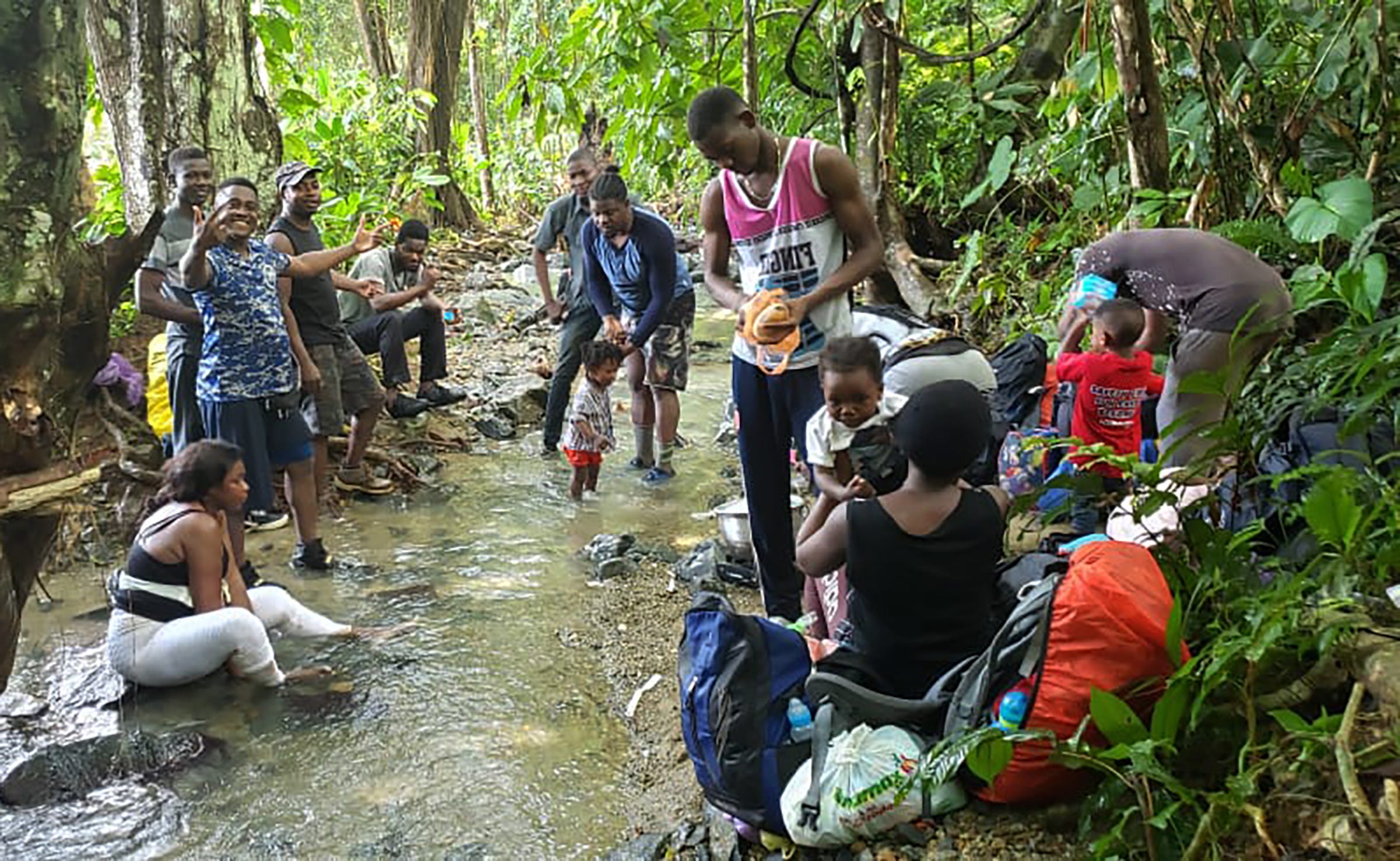 Williamson Simon, at center, holds his son as he travels north through the Darien Gap at the border between Panama and Colombia, in December 2019.