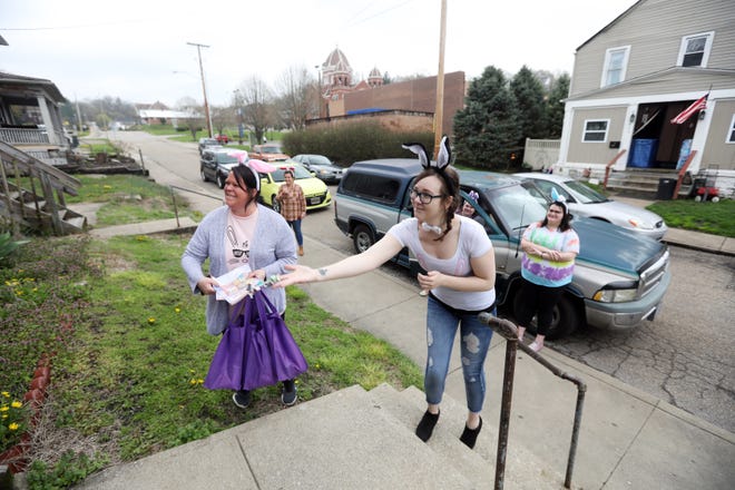 Ashley Newton, right, tosses candy onto a porch on Fountain Square in Zanesville as Dessie Craig and the rest of the Eastide Community Ministries Easter Parade members get ready to spread some Easter cheer.