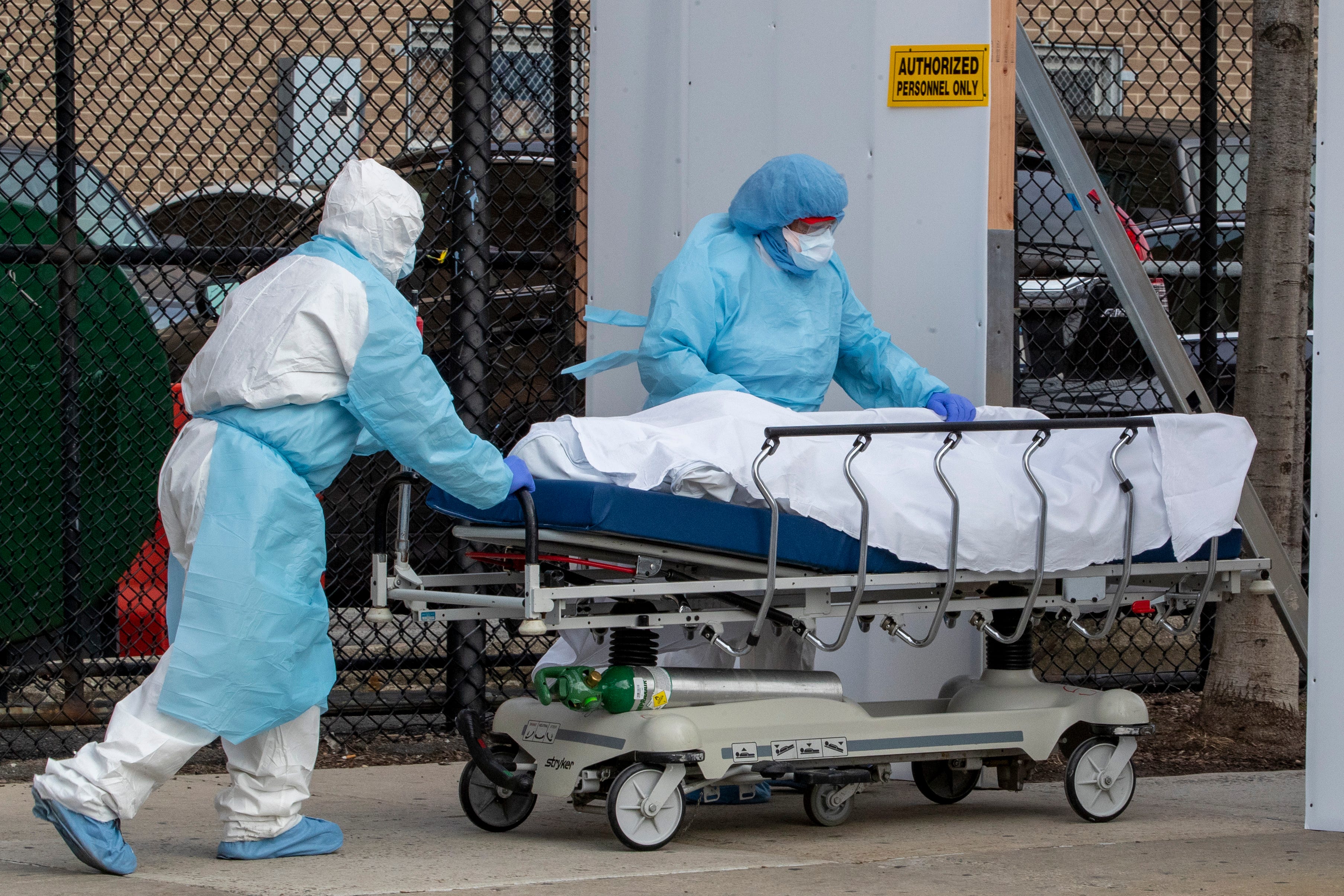 Medical personnel wearing personal protective equipment remove a body from the Wyckoff Heights Medical Center to refrigerated containers parked outside, Thursday, April 2, 2020, in the Brooklyn borough of New York. As coronavirus hot spots and death tolls flared around the U.S., the nation's biggest city was the hardest hit of the all, with bodies loaded onto refrigerated morgue trucks by gurney and forklift outside overwhelmed hospitals, in full view of passing motorists.