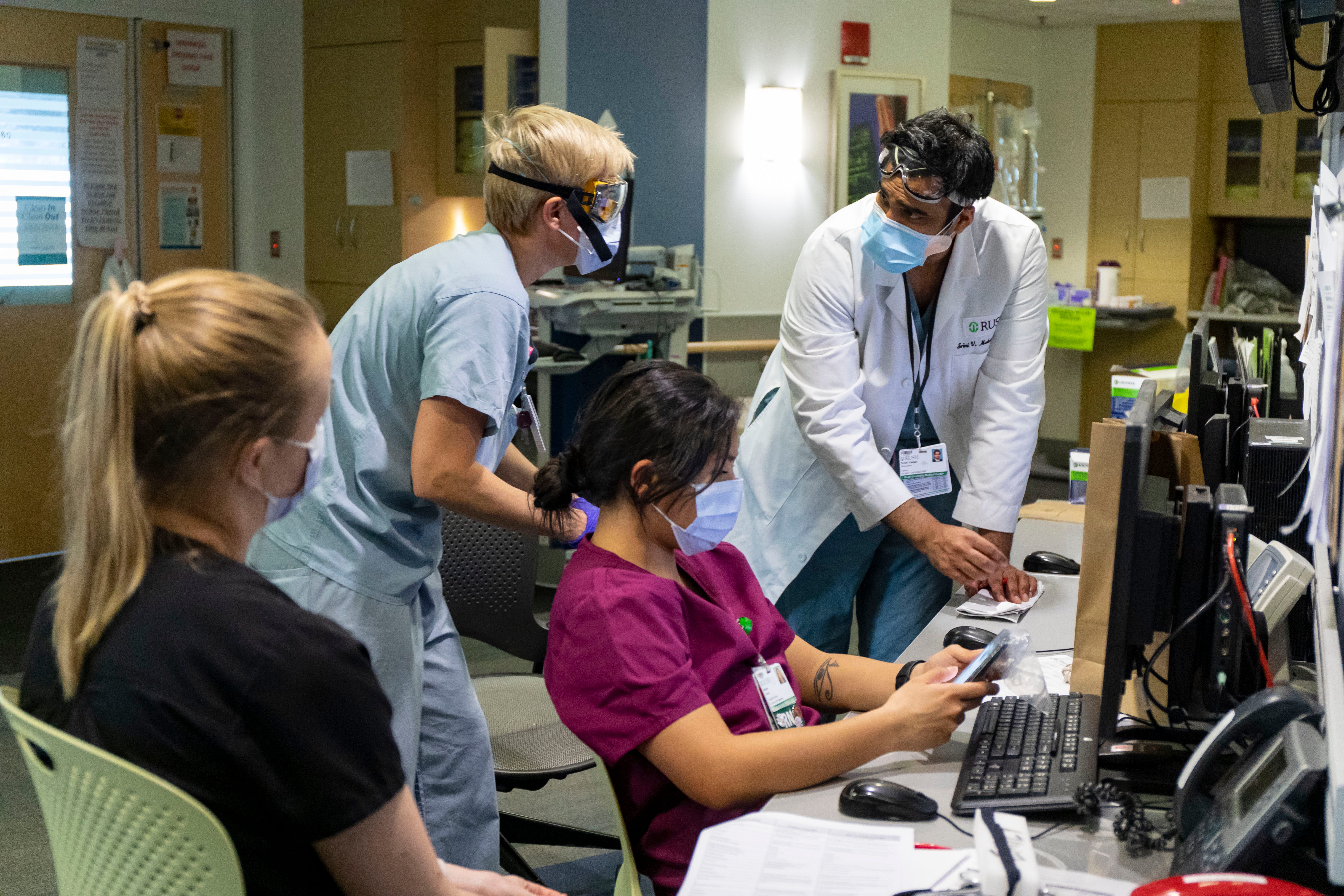 In this Tuesday, April 7, 2020 photo, Dr. Srini V. Mukundan, right, reviews COVID-19 patient information with other medical staff in the ICU at Rush University Medical Center in Chicago, during the coronavirus pandemic.