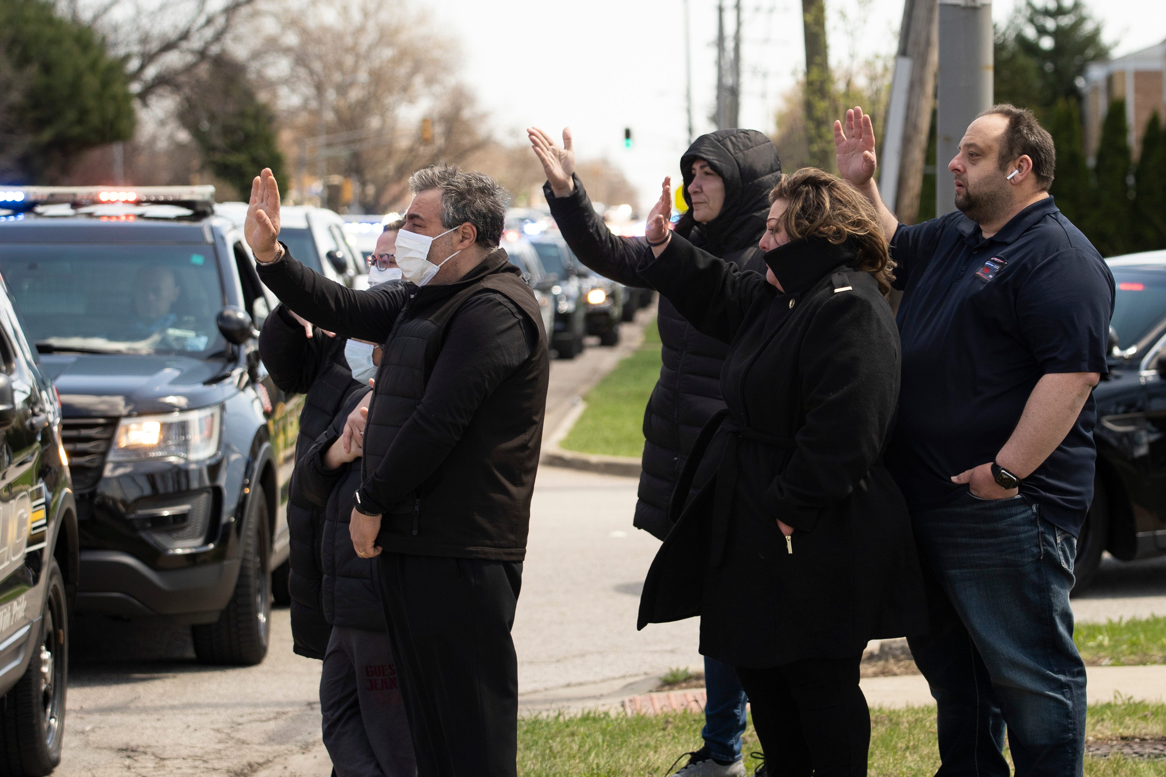 Family and friends of Chicago Police Officer Marco DiFranco, who had to stand outside during the funeral amid fears of the coronavirus pandemic, wave goodbye as the hearse leaves Cumberland Funeral Chapels, Thursday, April 9, 2020, in Norridge, Ilinois. DiFranco, 50, died April 2 from complications from COVID-19, making him the first Chicago police officer to lose his life to the coronavirus.