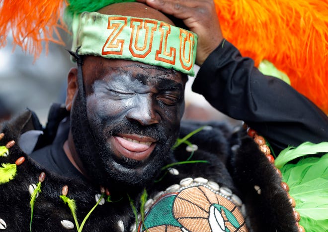 FILE - In this Feb. 13, 2018, file photo, a member of the Krewe of Zulu adjusts his hat as their parade rolls on Mardi Gras day in New Orleans. In a city ravaged by the coronavirus outbreak, Zulu and its members have paid a heavy price. Several of the group's members have died from coronavirus-related complications, said Zulu President Elroy A. James. Multiple other members have tested positive. (AP Photo/Gerald Herbert, File)