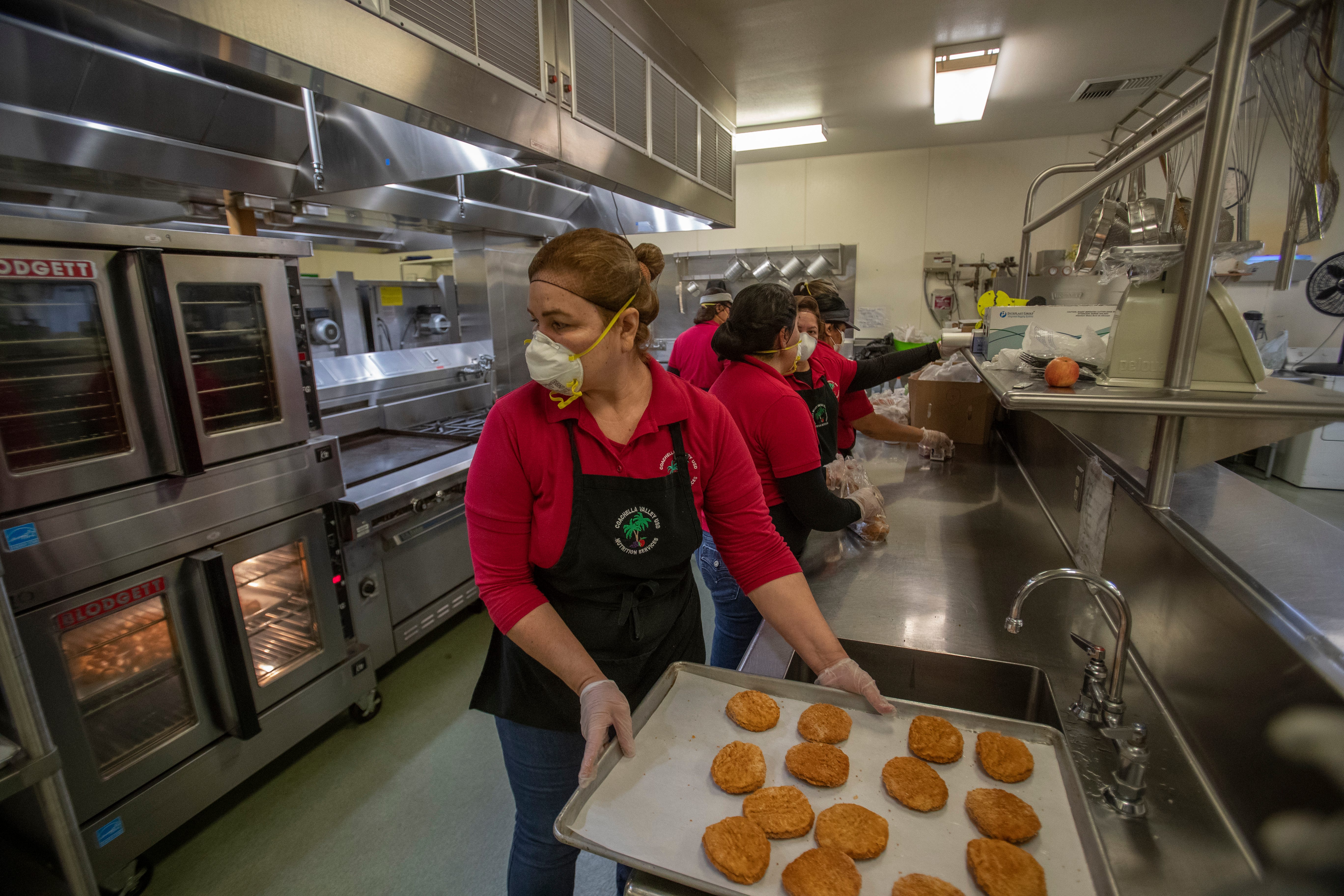 Food is prepared by Coachella Valley Unified School District employees to be load up on buses and distributed to students in the eastern Coachella Valley. 