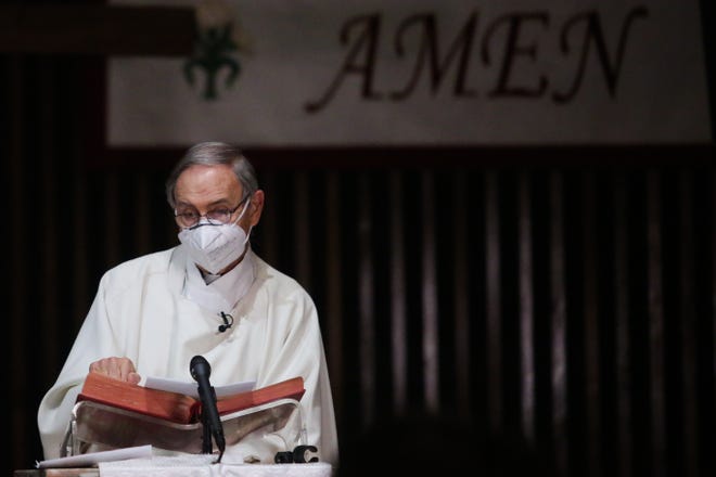 Reverend Monsignor Howard Lincoln of Sacred Heart Catholic Church wears a face mask on Easter Day before celebrating mass live on KMIR-TV due to California's stay-at-home order during the coronavirus outbreak on Sunday, April 12, 2020, in Palm Desert, Calif.