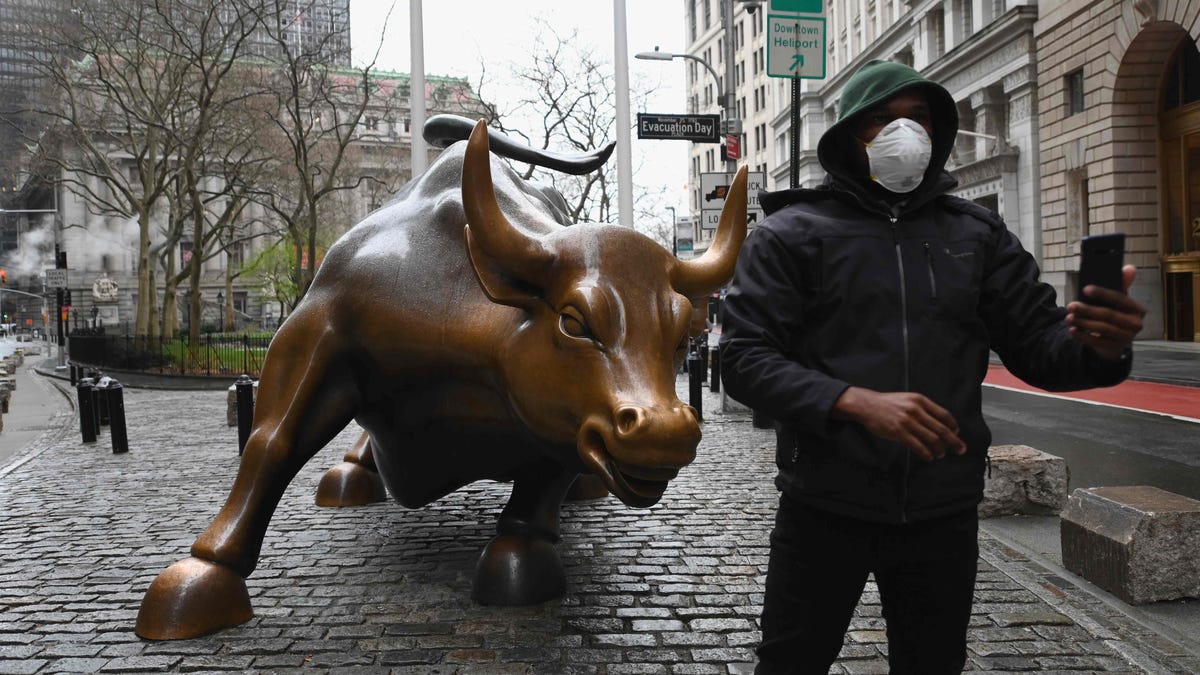 A man wearing a face mask takes a selfie at the Charging Bull statue on March 23, 2020  near the New Stock Exchange in New York City.