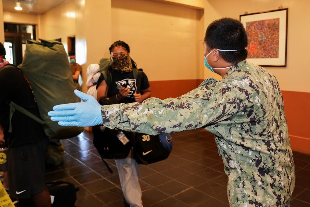 A sailor assigned to Commander, Submarine Squadron Fifteen directs sailors assigned to the aircraft carrier USS Theodore Roosevelt (CVN 71) who have tested negative for COVID-19 and are asymptomatic into the check-in line for room assignment at a Government of Guam and military-approved commercial lodging. Theodore Roosevelt sailors were moved to local hotels in an effort to implement an aggressive mitigation strategy to minimize the spread of COVID-19 and protect the health of the sailors. Sailors remain in quarantine in their assigned lodging for at least 14 days, in accordance with DoD directive and the governor's executive order.