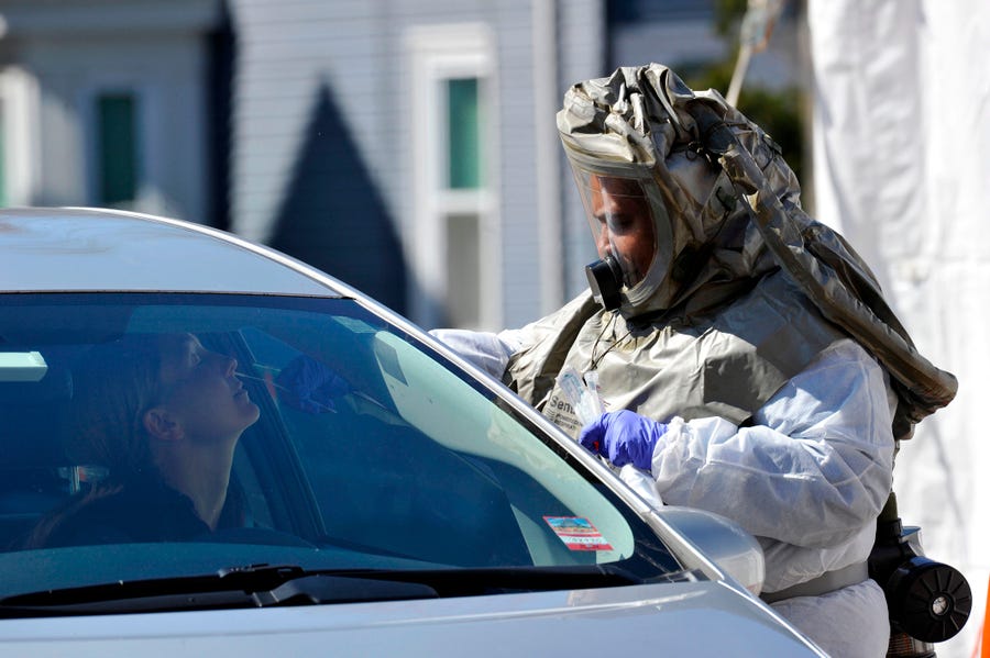A nurse in a hazmat suit swabs a woman's nose during a test for coronavirus at Somerville Hospital in Massachusetts.