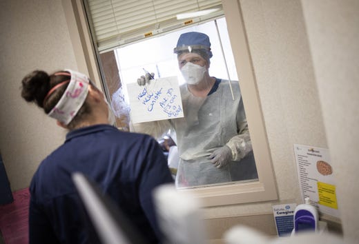 To reduce the number of times a patient's room door is opened and the amount of personal protective equipment required, nurses in the intensive care unit of MedStar St. Mary's Hospital communicate through a window with an erasable whiteboard from a COVID-19 patient's room on April 14, 2020 in Leonardtown, Maryland.