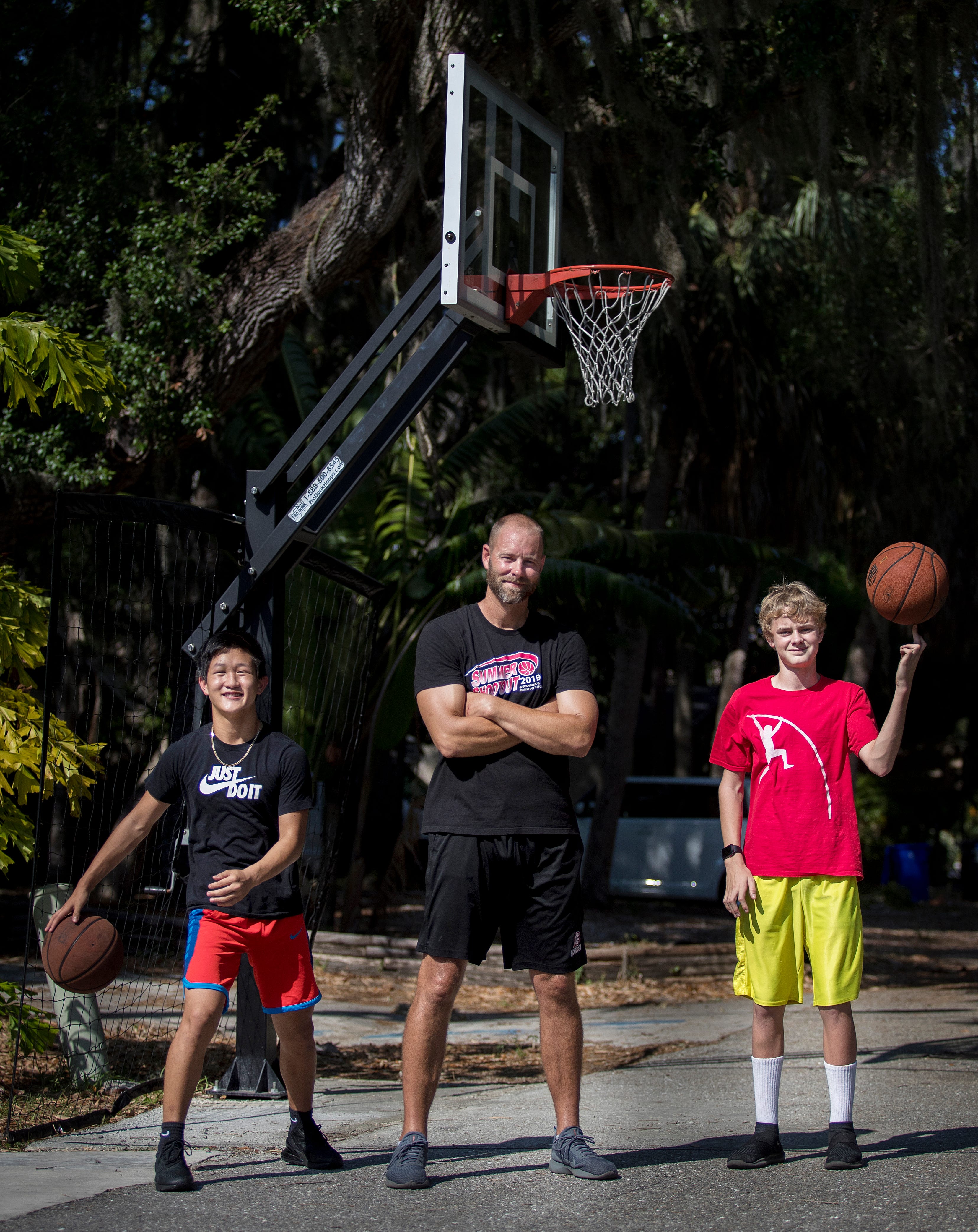 Scott Guttery, athletic director and basketball coach at Evangelical Christian School, and his sons Trae, 14, left, and Reece, 15, on Tuesday, April 14, 2020. The family has been quarantined but decided to stay active by challenging each other to do different basketball trick shots in their driveway. They call it "Trick Shot Tuesday."
"Trick Shot Tuesday has been a fun diversion for me and an opportunity to do something fun with my family," said Scott Guttery, adding that he has also spread the challenge to ECS sports teams and other schools. He is using the time to be with family, praying and reading God's word, he said. "I hope that our country, city, and the entire world can recover from this as soon as possible. I also hope it draws people closer to God and their families. With no sports taking place, I am way ahead on my scheduling and planning for next school year.  All of our season schedules for next year are complete," Scott Guttery said.