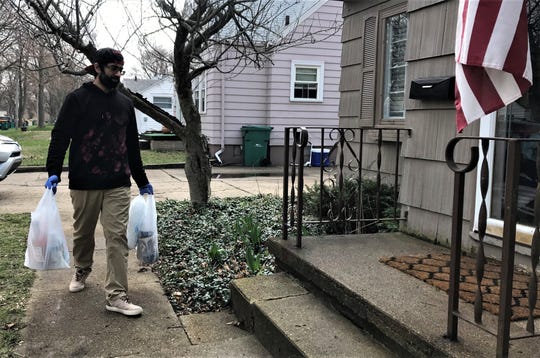 Karmvir Singh Gill of Battle Creek Liquor Delivery brings a delivery to a doorstep in Battle Creek on Tuesday, April 7, 2020.