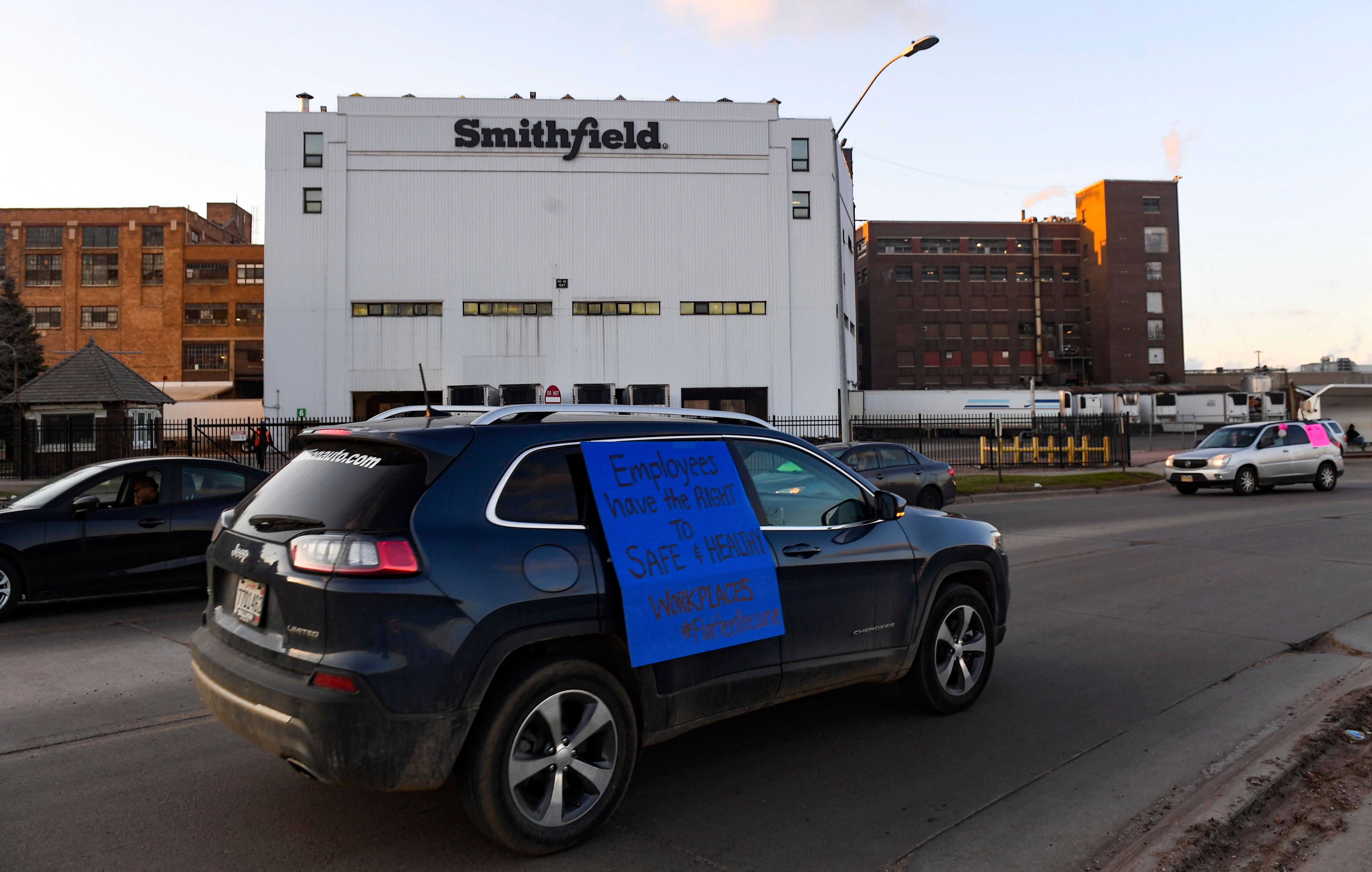 A car sporting a sign calling for a safe and healthy workplace drives past Smithfield Foods in Sioux Falls, S.D., on April 9, 2020, during a protest on behalf of employees after many workers complained of unsafe working conditions amid the COVID-19 outbreak. The pork processing plant in South Dakota closed temporarily after more than 80 employees tested positive for the coronavirus.