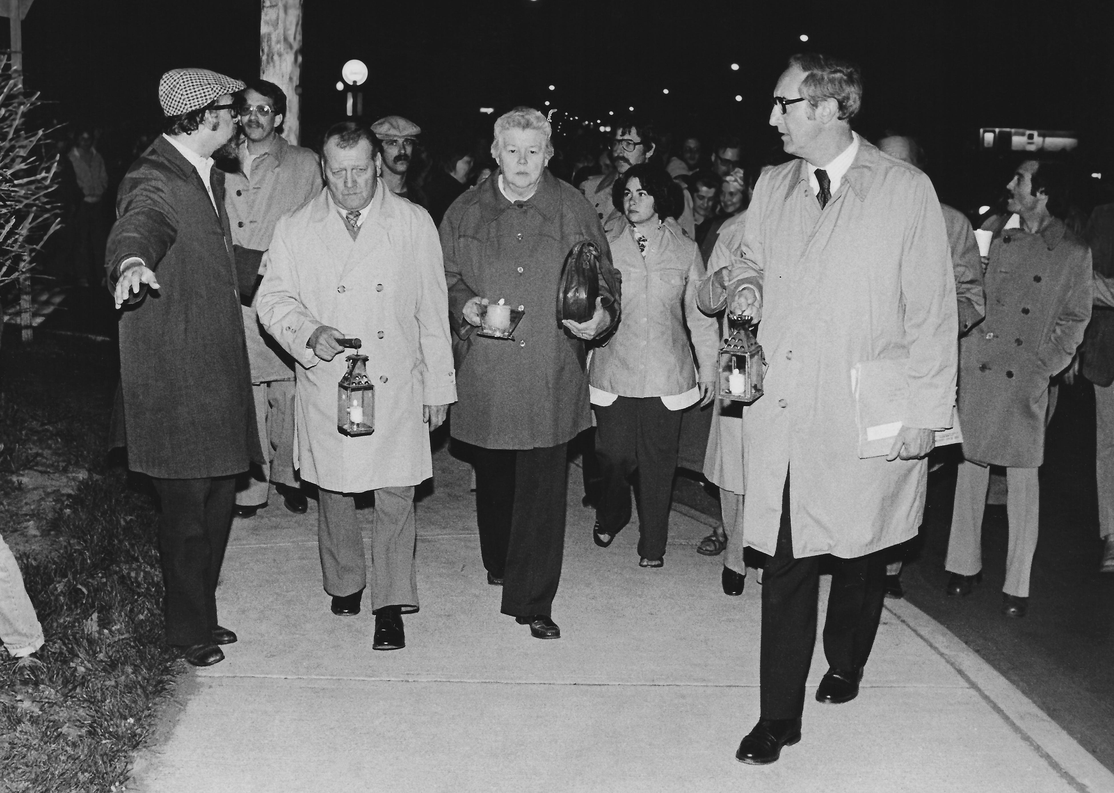 Sociology professor Jerry Lewis (left) points the way for Lou and Florence Schroeder, parents of slain Kent State student William Schroeder, during the annual candlelight vigil march on May 4, 1978. At right is Glenn Olds, the university president.