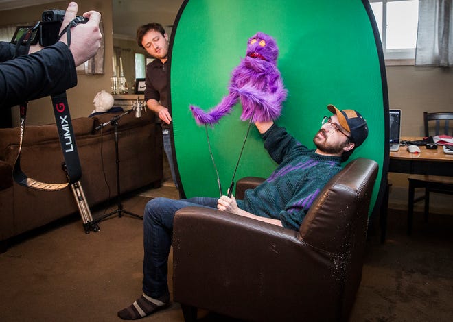 Max Cseresznyes (left) holds a green screen while Nicholas Rohrman operates a puppet while filming a video in their apartment on University Avenue Friday, April 17, 2020. 