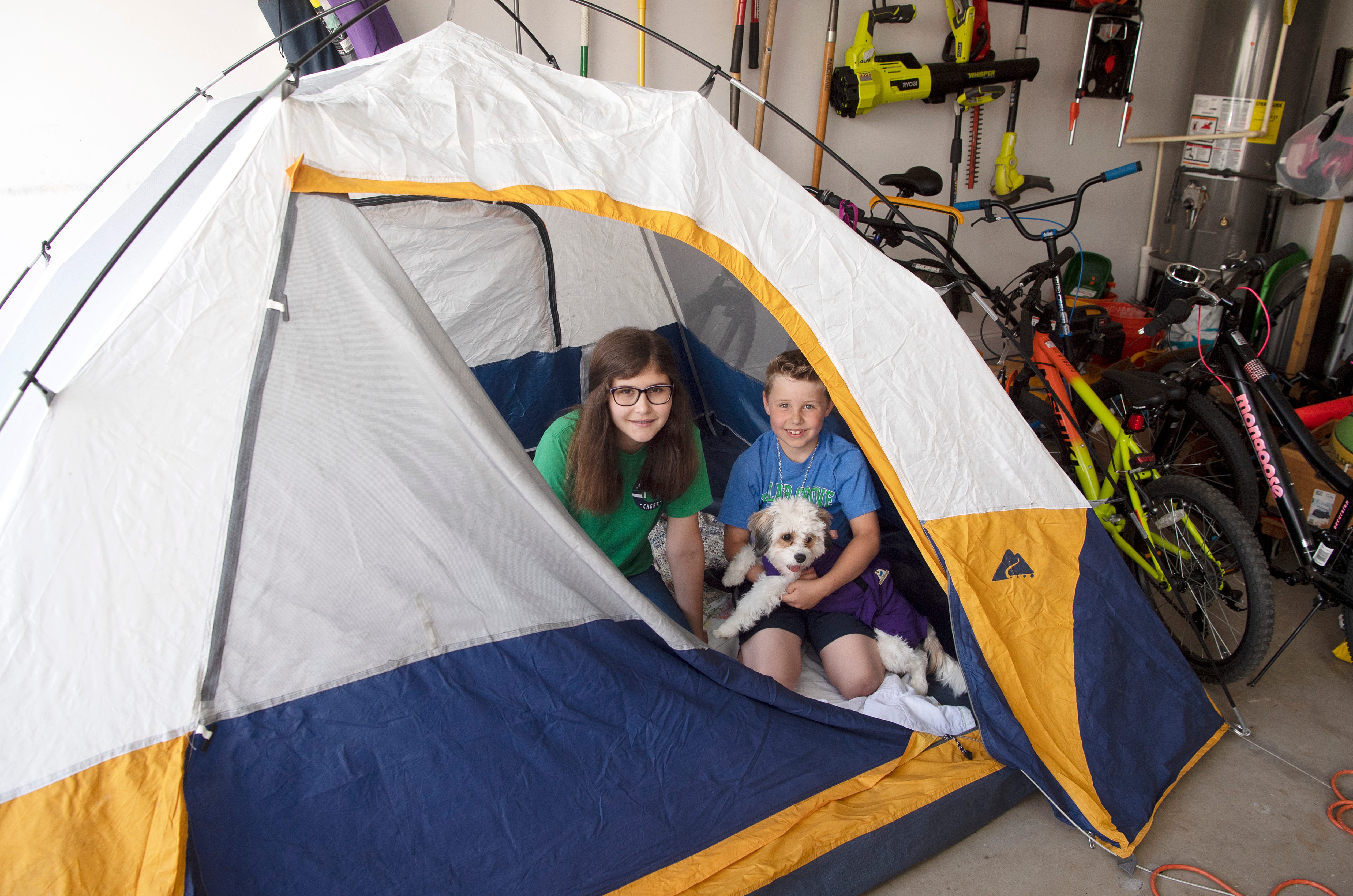 Poplar Grove Middle School sixth grader Annelise Wilson, of Franklin, and her brother, first grader Ian Wilson, put up a tent in which to do their homework after their school closed. The tent has moved from the backyard to the front yard to the garage.