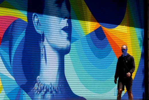 A pedestrian uses a face cover while walking in downtown Durham, N.C., Friday, April 17, 2020. Gov. Roy Cooper's stay-home orders remain in effect as the coronavirus has not yet reached its peak in the state according to some hospitals.