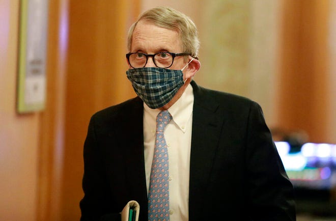 Wearing his protective mask made by his wife, Ohio Gov. Mike DeWine walks into his daily coronavirus news conference on Thursday, April 16, 2020, at the Ohio Statehouse in Columbus, Ohio. (Doral Chenoweth/The Columbus Dispatch via AP)