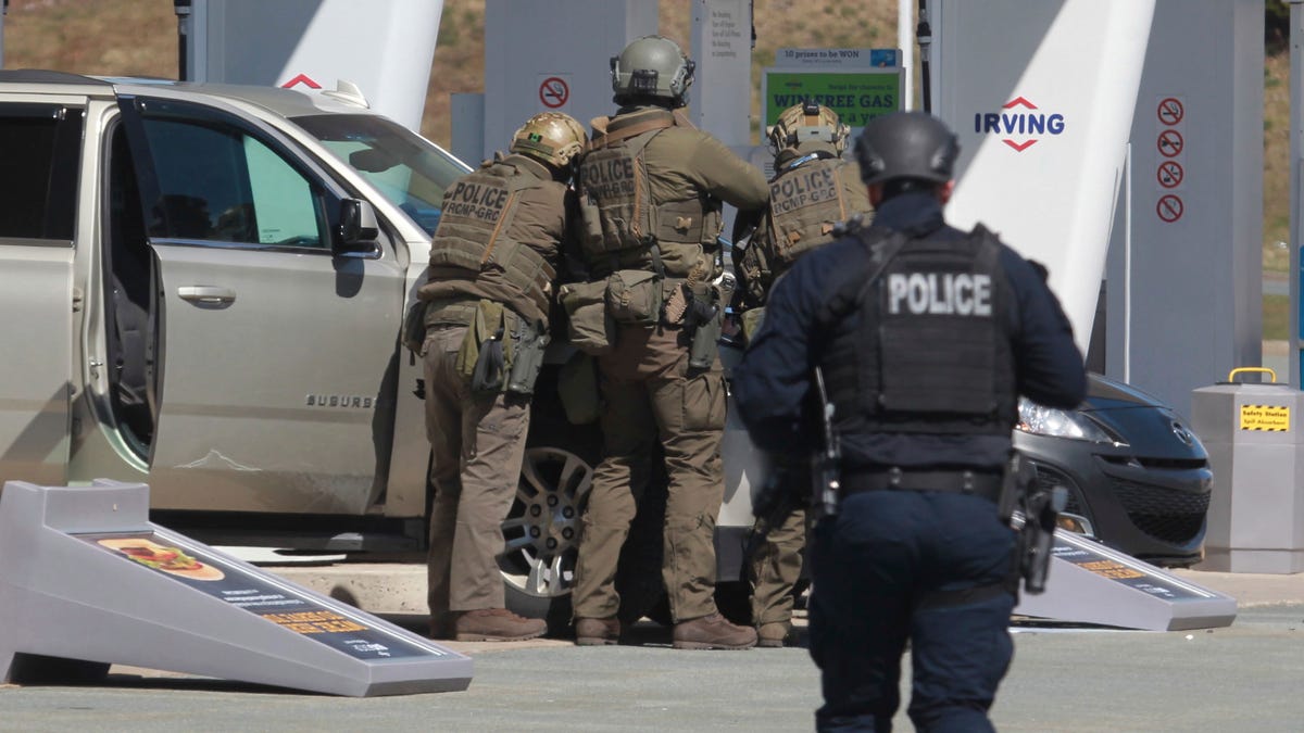 Royal Canadian Mounted Police confront a suspect at a gas station in Enfield, Nova Scotia, on April 19. A gunman disguised as a police officer shot people in their homes and set fires in a rampage across the Canadian province. Officials said Sunday the suspected shooter was  dead.