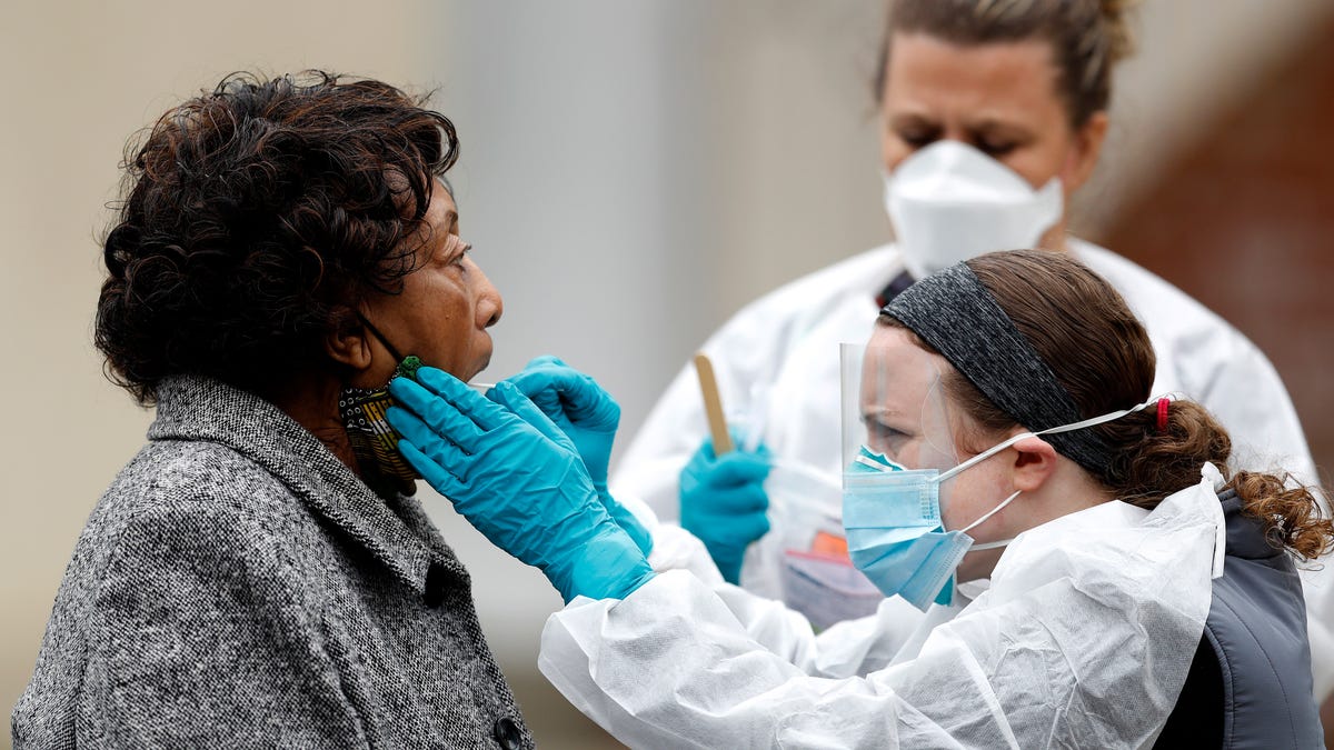 Alma Cropper, 84, left, is given a coronavirus test near her vehicle at a walk-up testing center, April 20, 2020, in Annapolis, Md. According to the City of Annapolis Office of Emergency Management, the testing site began with a limited number of tests for people with symptoms on Monday.