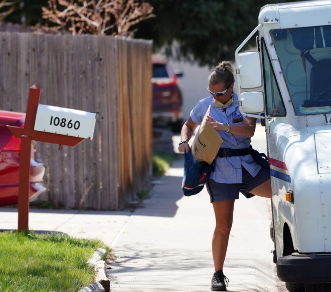 U.S. Postal Service carrier Amy Bezerra loads mail, including an Amazon package, into her delivery pouches along her route in suburban Denver.
