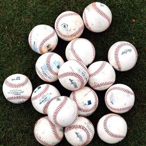 A stack of baseballs sit on the field.