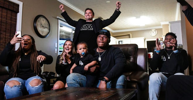 Former Auburn defensive tackle Derrick Brown (center, holding son Kai) celebrates getting picked seventh in the NFL Draft along with his girlfriend, members of his family and his agent on April 23, 2020, at his family home in Atlanta, Georgia.