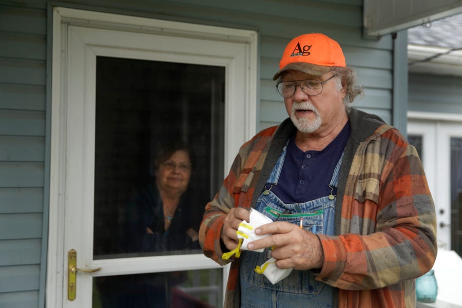 Dennis holds two of his remaining N95 masks as he stands with his wife, Sharon, at their home near Troy, Kansas, on Friday, April 24, 2020. Dennis, a retired farmer, shipped one of the couple's five masks left over from his farming days to New York Gov. Andrew Cuomo for use by a doctor or a nurse.