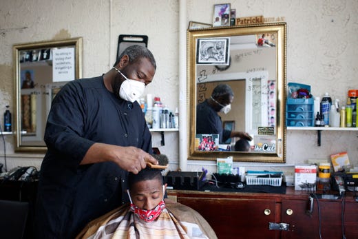 Barber Patrick Watkins of Jet Cuts & Styles finishes up a haircut on Darrell Stevens at the reopened barbershop in Athens, Ga, on Friday, April 24, 2020. The shop is one of the first non-essential businesses in Athens to open following Gov. Brian Kemp’s announcement to ease his COVID-19 emergency declaration. 